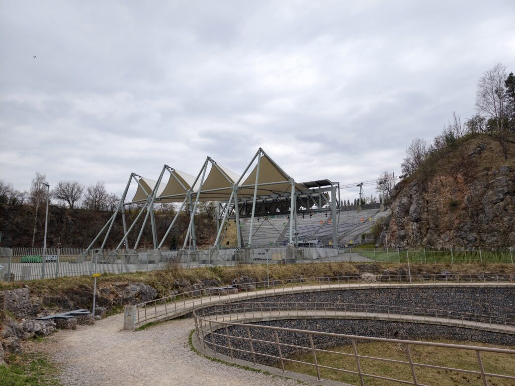 Zmodernizowany Amfiteatr na Kadzielni z nowoczesnym zadaszeniem w kształcie chmur, wkomponowany w wysokie, wapienne zbocza.