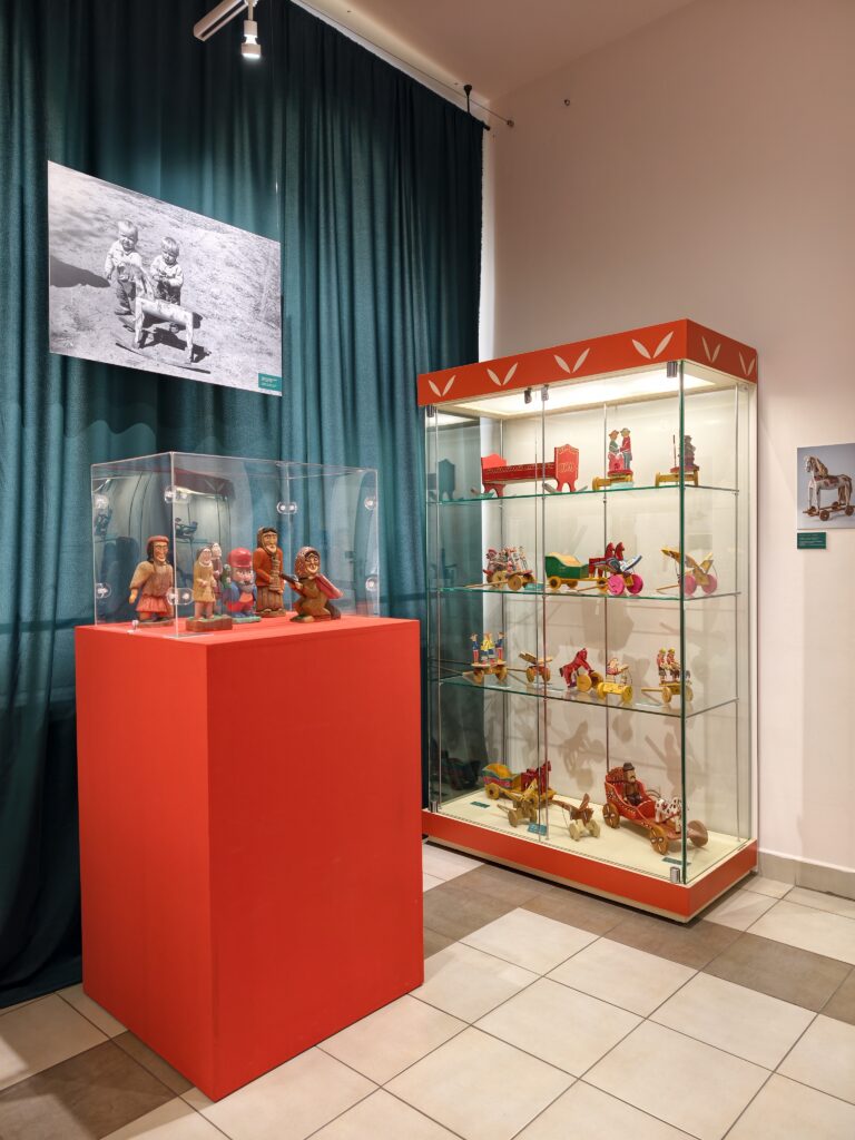 Gablota z ekspozycyjną w muzeum, prezentująca stare, drewniane zabawki.