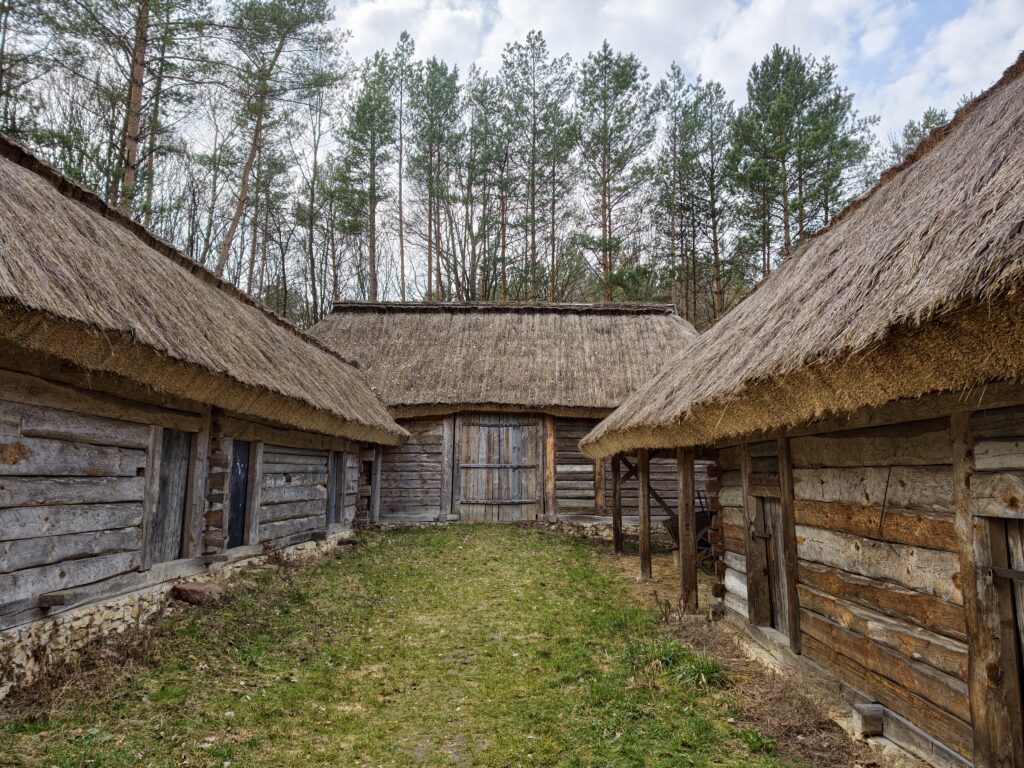 Wewnętrzny dziedziniec tradycyjnej zagrody chłopskiej krytej strzechą w skansenie w Tokarni