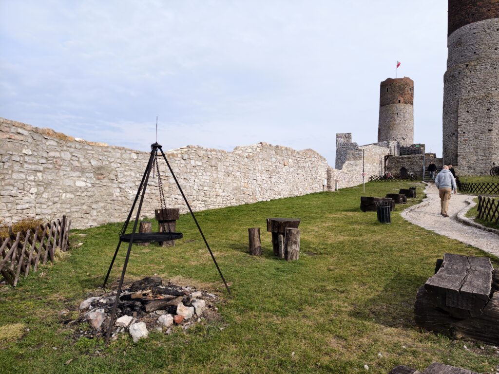 Przestronny dziedziniec Zamku w Chęcinach z wyznaczonym miejscem na palenisko w otoczeniu kamiennych murów