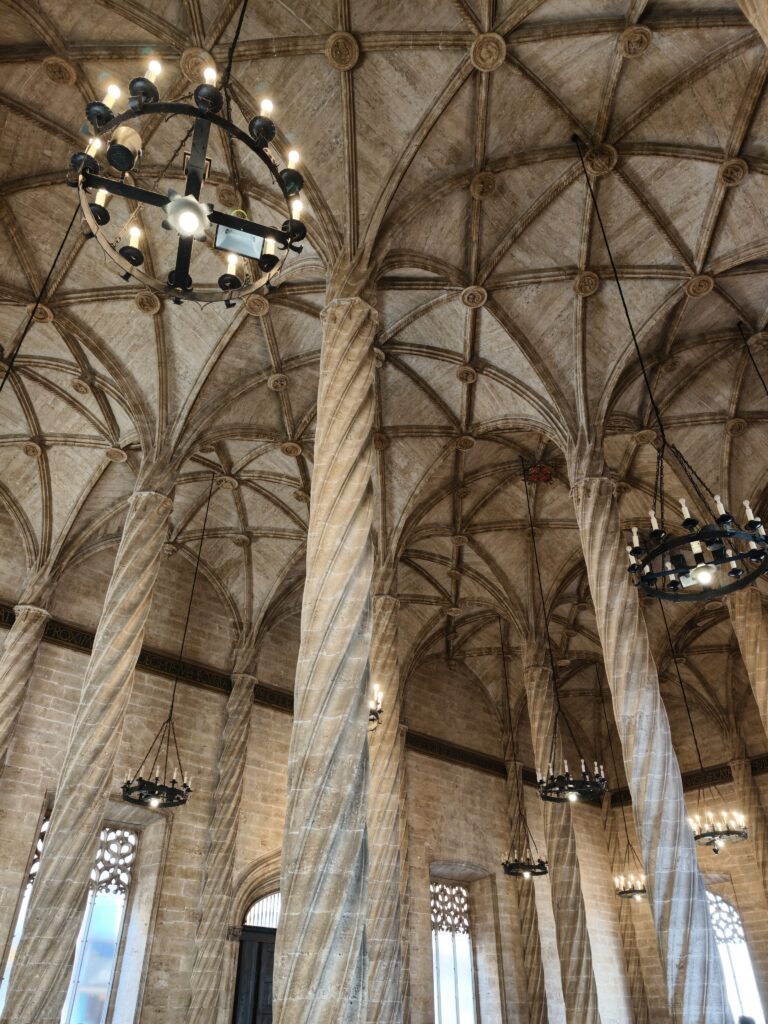 Jasne, gotyckie wnętrze głównej sali handlowej w Giełdzie Jedwabiu w Walencji z rzędem wysokich, kamiennych kolumn skręconych na kształt lin.