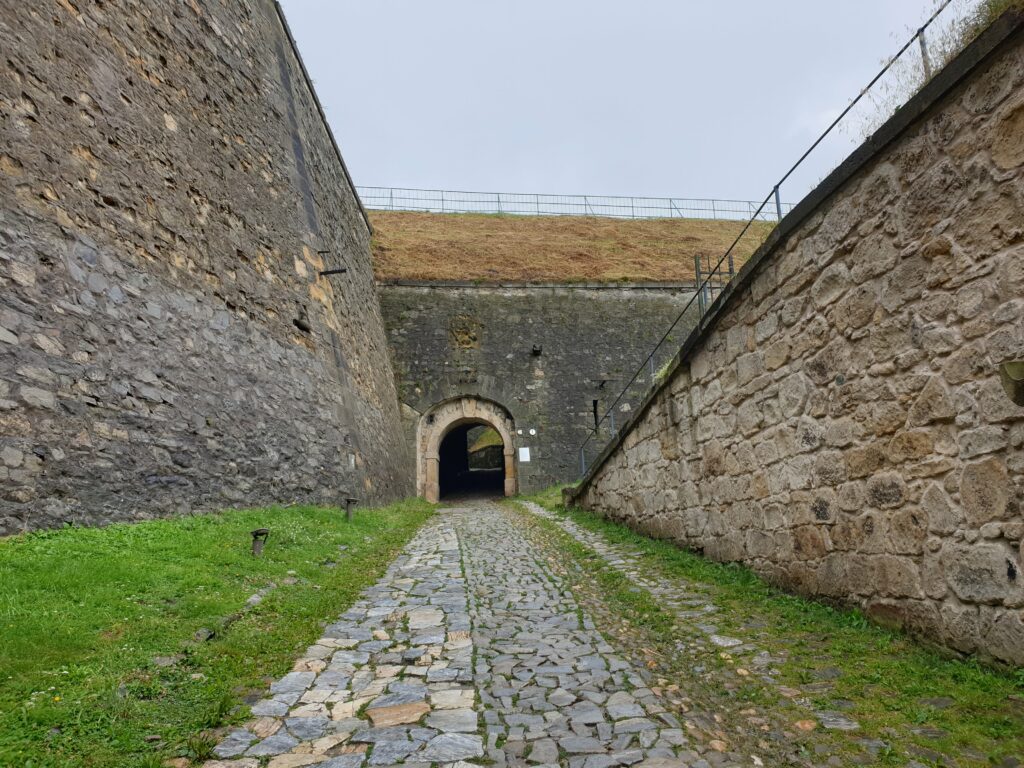 Zabytkowe brukowe ścieżki w kłodzkiej twierdzy na tle potężnych murów.
