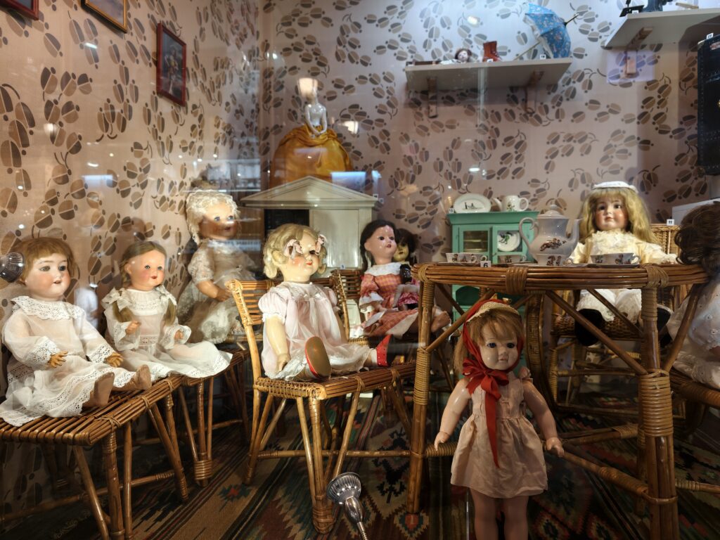 Gablota z kolekcją starych lalek porcelanowych i celuloidowych w misternie uszytych, tradycyjnych strojach z XIX i XX wieku.