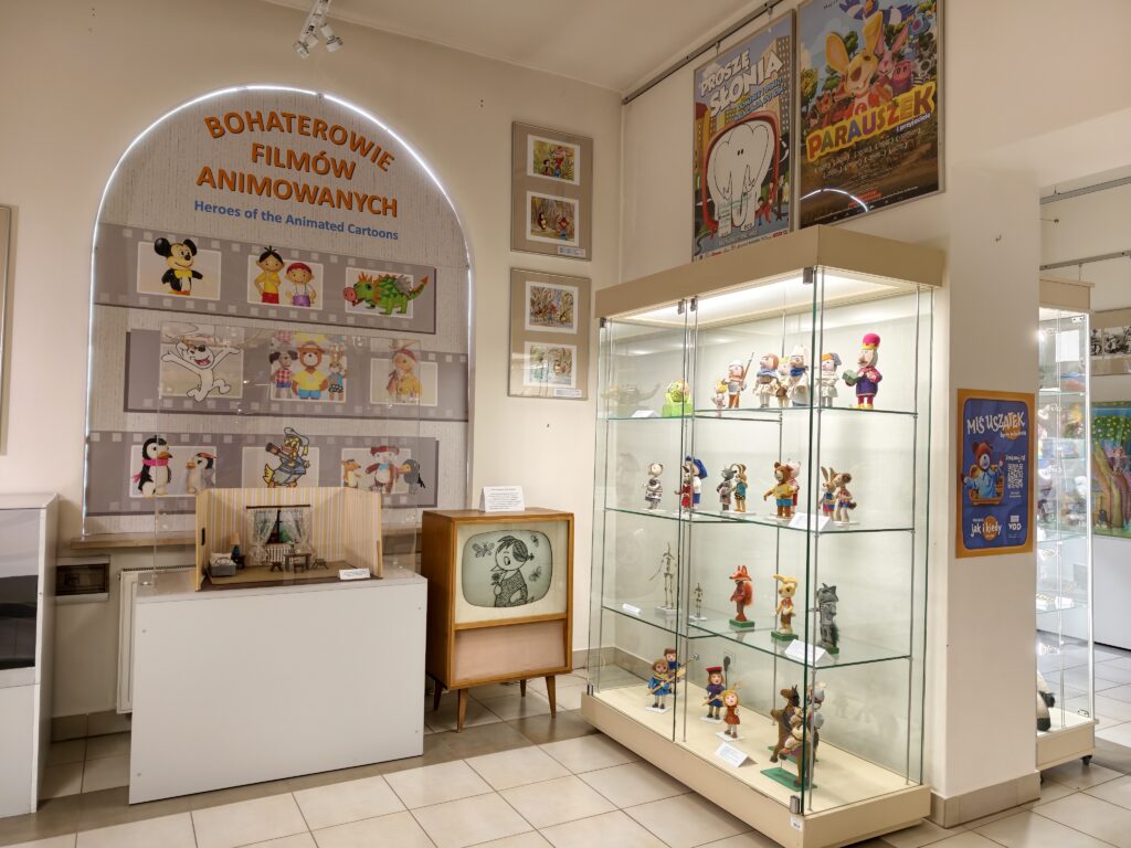 Kolorowa ekspozycja kultowych zabawek z czasów PRL, w tym kultowe postacie z bajek, metalowe modele pojazdów i gry planszowe w Muzeum Zabawek i Zabawy w Kielcach.