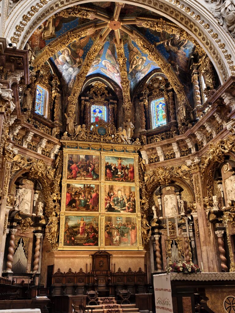 Bogato zdobiony ołtarz główny w Katedrze w Walencji, otoczony wspaniałymi renesansowymi freskami i rzeźbieniami ze złota, oświetlony wewnątrz mrocznej świątyni.