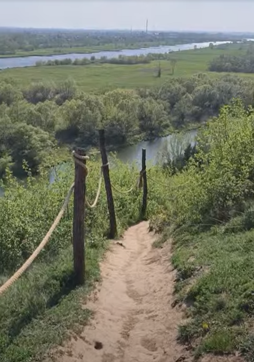 Stroma, piaszczysta ścieżka zabezpieczona drewnianymi palikami i grubą liną, prowadząca w dół ku dolinie Wisły.