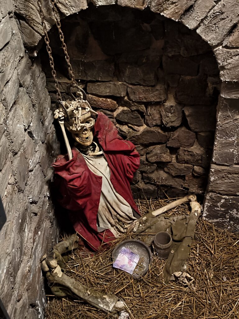 Realistyczna ekspozycja szkieletu zakutego w łańcuchy w mrocznych lochach Zamku w Chęcinach