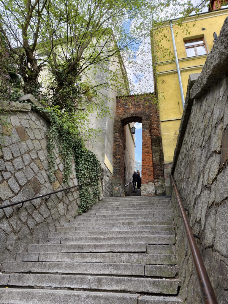 Turysta przeciskający się przez bardzo wąskie, ceglane przejście w sandomierskim Uchu Igielnym.