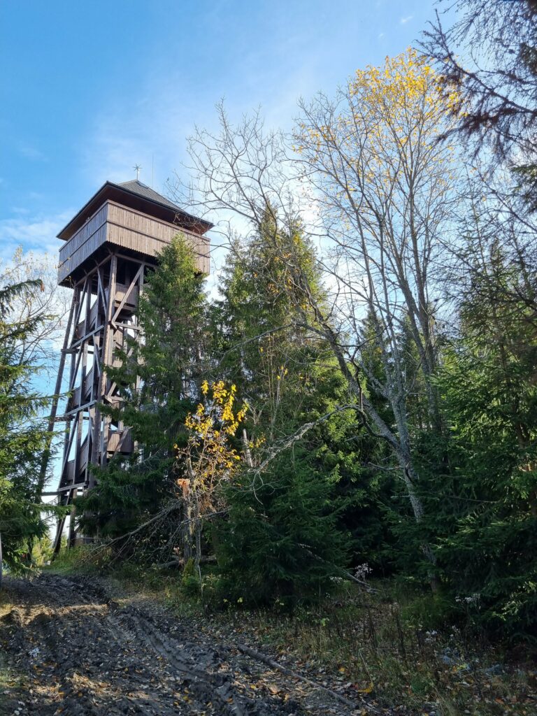 Drewniana wieża widokowa o solidnej konstrukcji stojąca na szczycie Magurek na tle nieba.