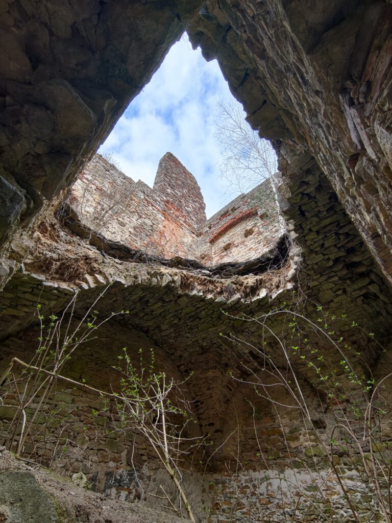 Imponujący widok z dołu do góry na zrujnowane narożne wieże Pałacu Tarłów pod błękitnym niebem.