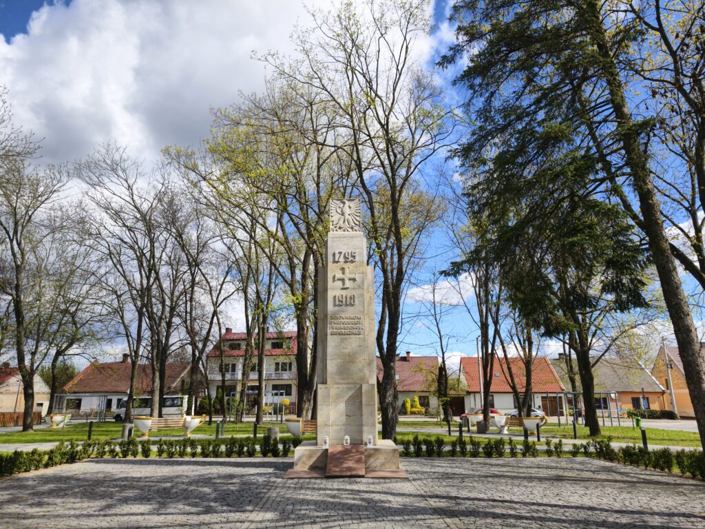 Kamienny pomnik bojownikom o niepodległość z orłem i datami 1795-1918 na skwerze w Ćmielowie.