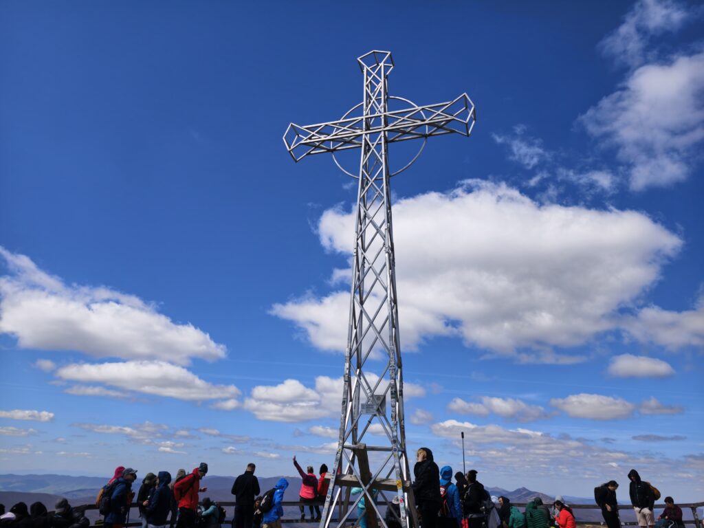 Widok na krzyż na szczycie Tarnicy z tłumem ludzi
