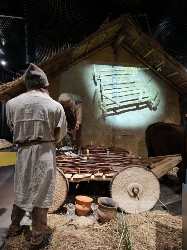 Rekonstrukcja neolitycznego wozu z figurami ludzi w muzeum Krzemionki Opatowskie – diorama przedstawiająca życie codzienne