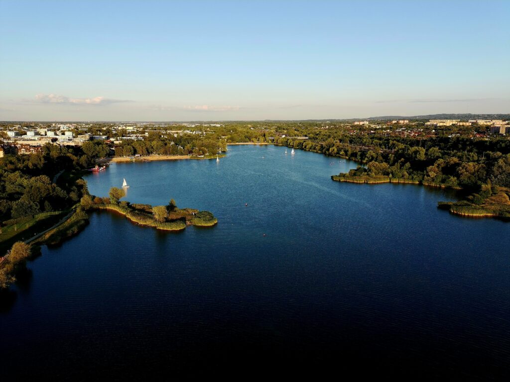Zalew Bagry w Krakowie z lotu ptaka - żaglówki, trzcinowe wysepki i piaszczysta plaża