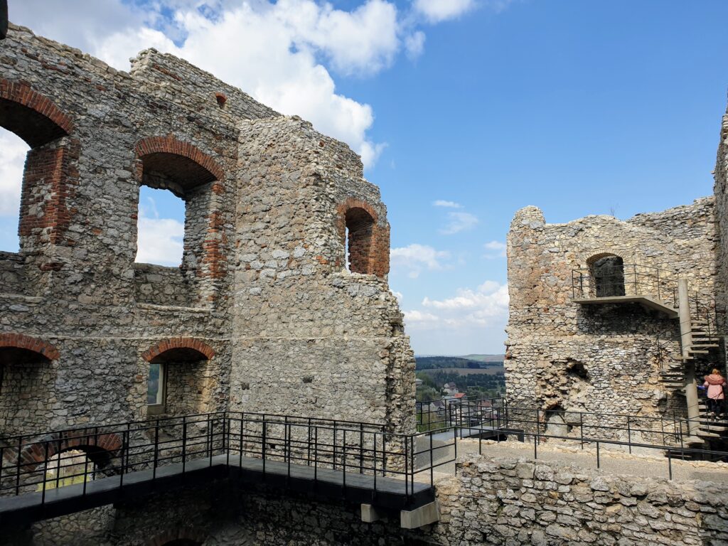 Ceglane okna i metalowe pomosty Zamku Ogrodzieniec z panoramą Podzamcza w tle