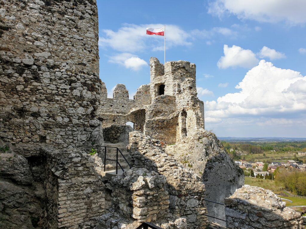 Górne partie Zamku Ogrodzieniec z polską flagą i panoramą Jury Krakowsko-Częstochowskiej