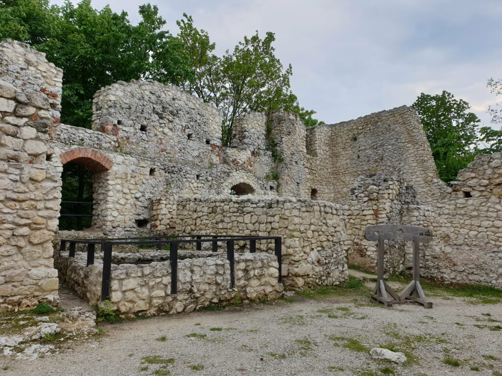 Wnętrze ruin zamku w Smoleniu – ceglany łuk, dawna studnia i drewniane dyby