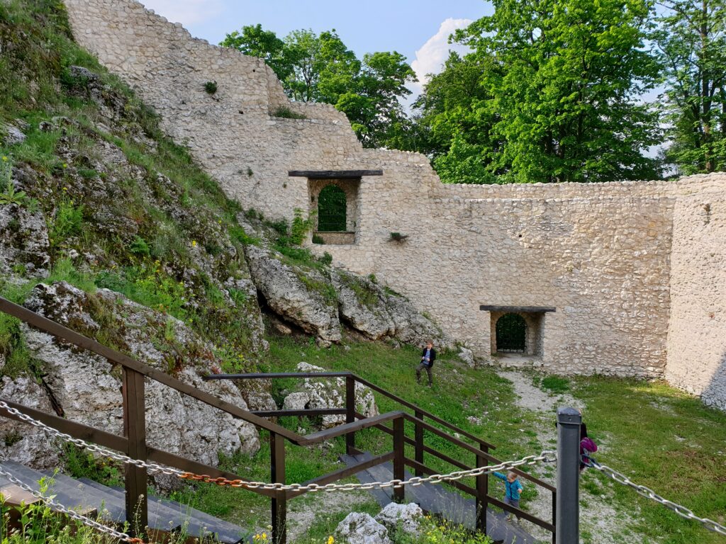 Dolny dziedziniec zamku w Smoleniu z drewnianymi schodami i dziećmi zwiedzającymi ruiny