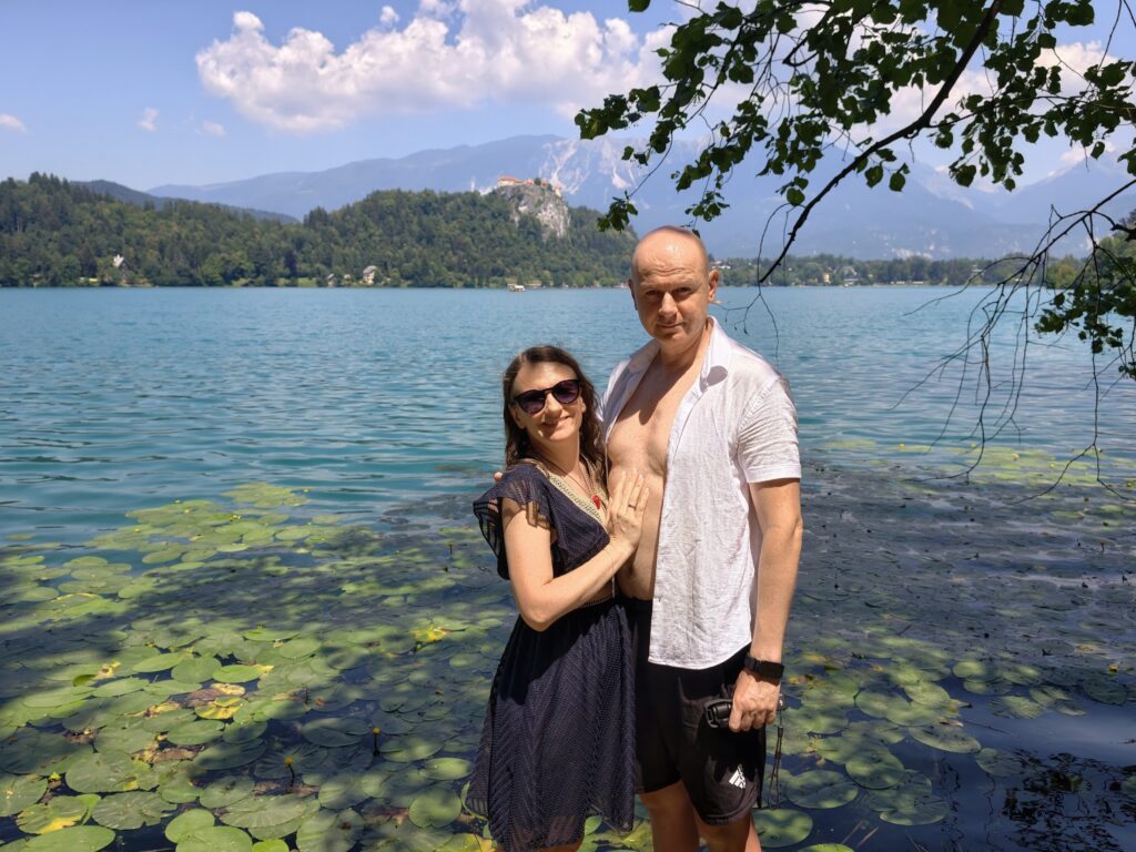 Para nad brzegiem jeziora Bled wśród lilii wodnych, zamek Bled w tle
