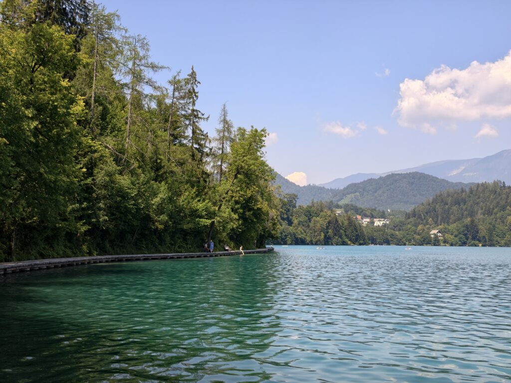 Drewniany pomost nad brzegiem jeziora Bled podczas spaceru wokół jeziora