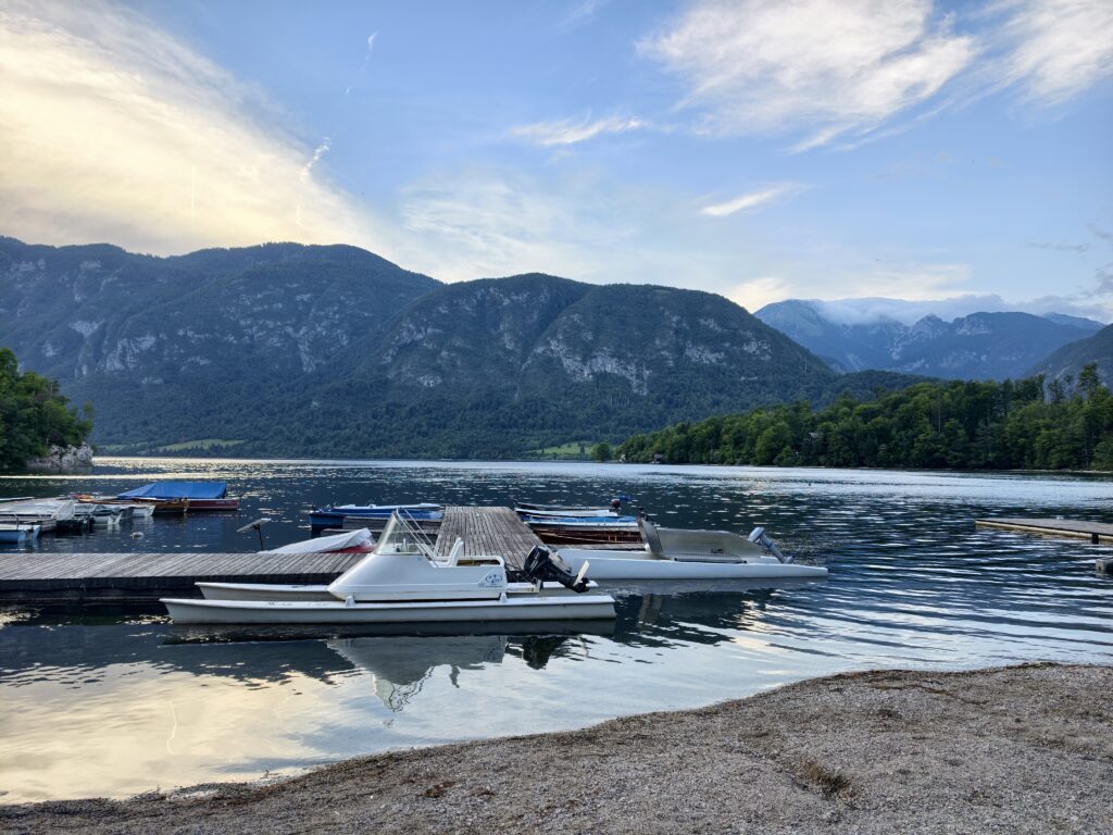 Łódki zacumowane przy drewnianym pomoście na jeziorze Bohinj o zachodzie słońca