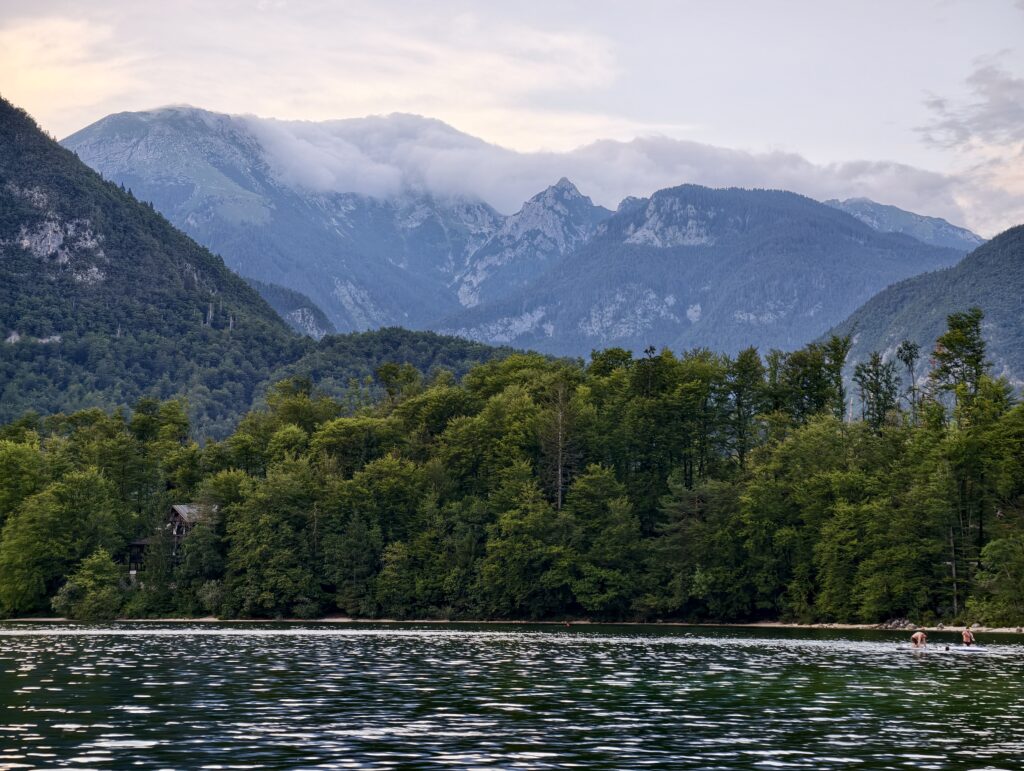 Mgła unosząca się nad górami przy jeziorze Bohinj, osoby na paddleboardach