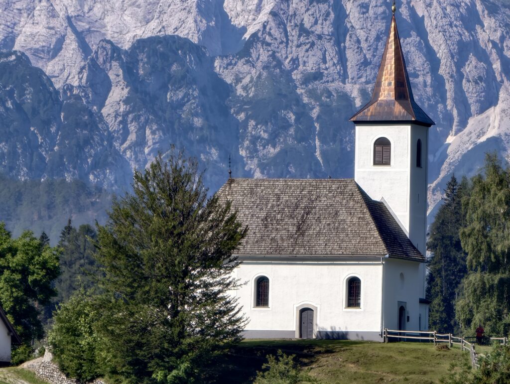 Zbliżenie na biały kościół z miedzianym dachem na tle pionowych skalnych ścian