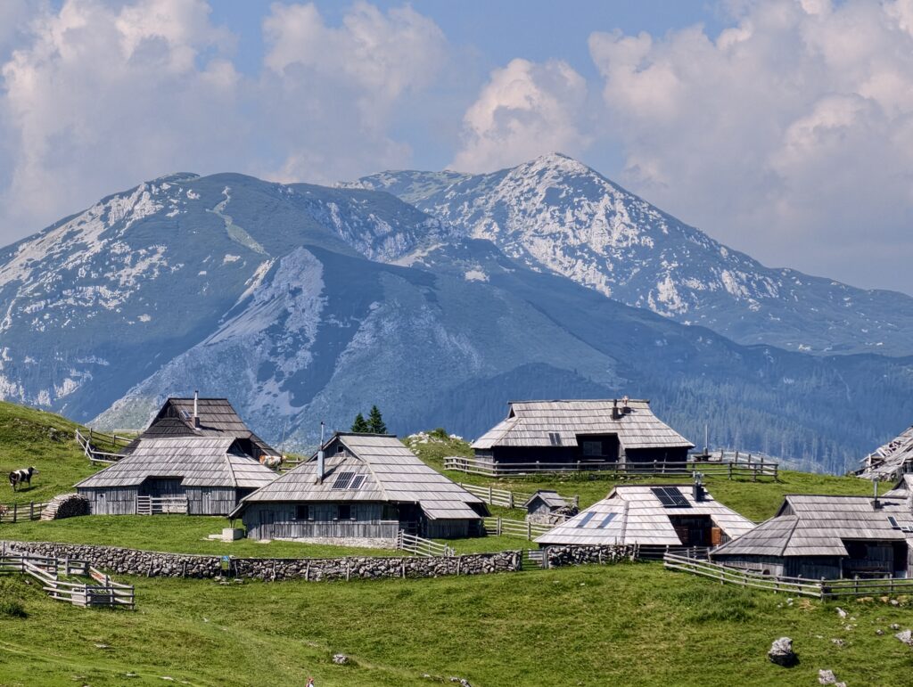 Chaty pasterskie na Velika Planina na tle szczytów Alp Kamnicko-Sawińskich