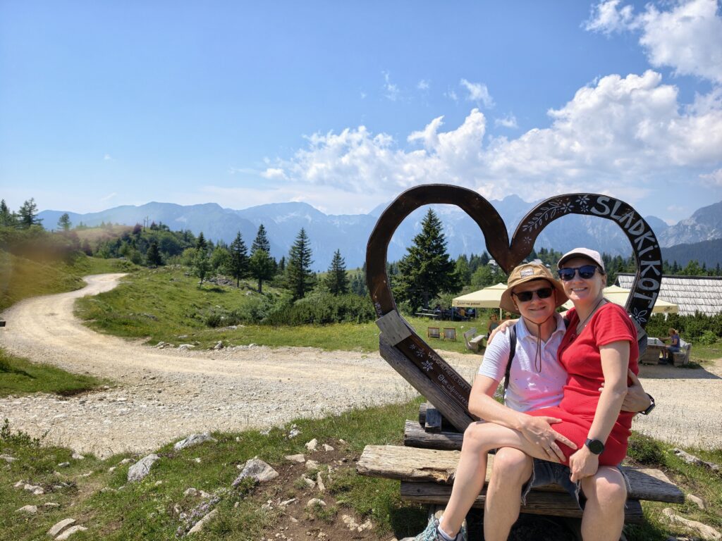 Para turystów przy drewnianym sercu na płaskowyżu Velika Planina w Słowenii