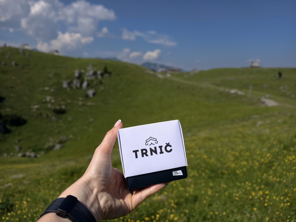 Ser Trnič ze Słowenii trzymany w dłoni na tle łąki na Velika Planina