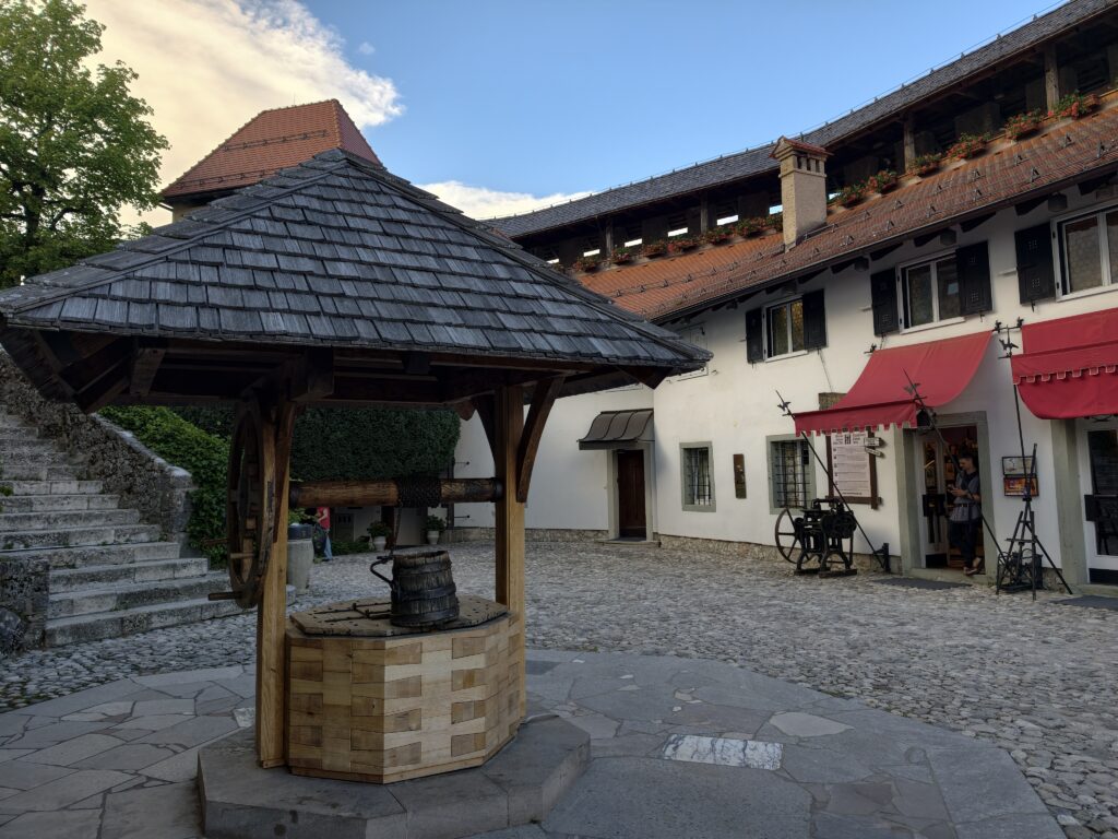 Dziedziniec zamku Bled z zabytkową studnią i drewnianym zadaszeniem
