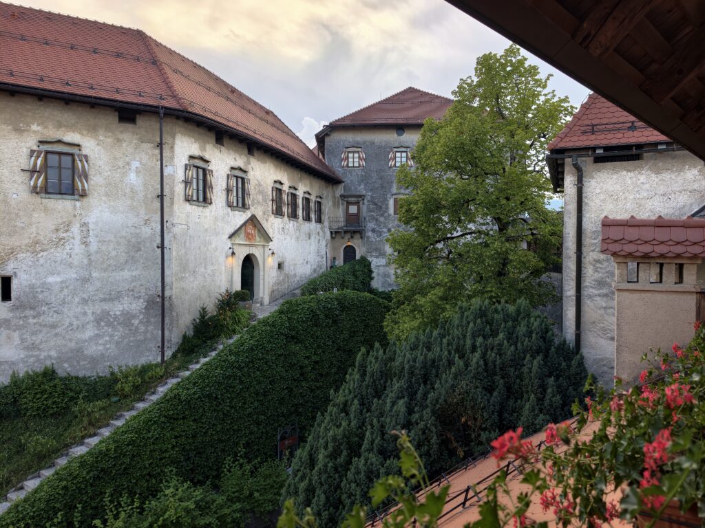 Mury i ogród zamku Bled o zmierzchu z widokiem na zabudowania