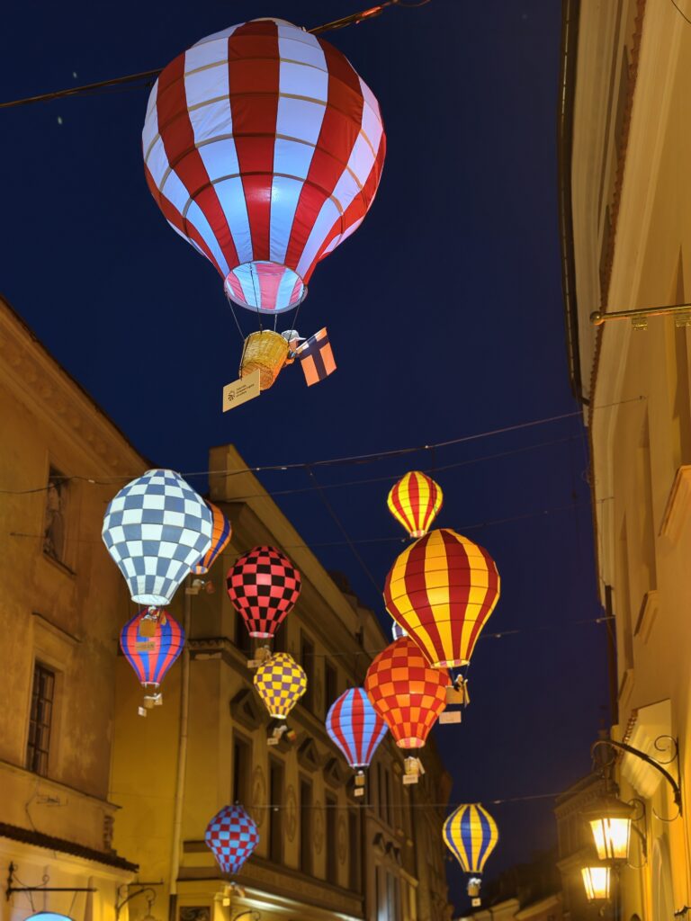 Kolorowe dekoracyjne balony zawieszone nad uliczką lubelskiej starówki podczas wieczornego spaceru