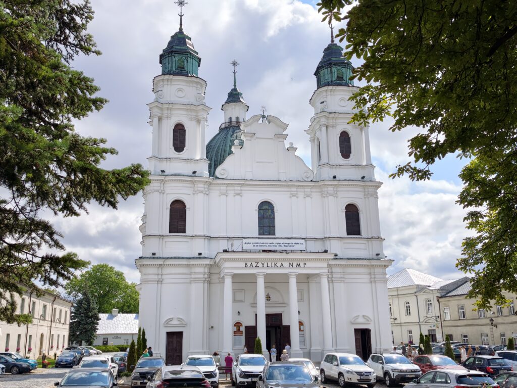 Biała fasada Bazyliki Narodzenia Najświętszej Maryi Panny na Górce Chełmskiej z napisem "Bazylika NMP" jako atrakcja w Chełmie