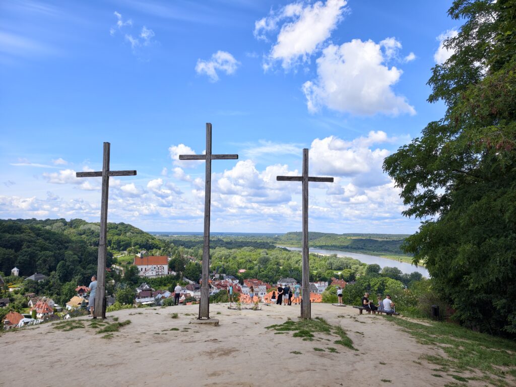 Trzy drewniane krzyże na Górze Trzech Krzyży z panoramą Kazimierza Dolnego i Wisły w tle