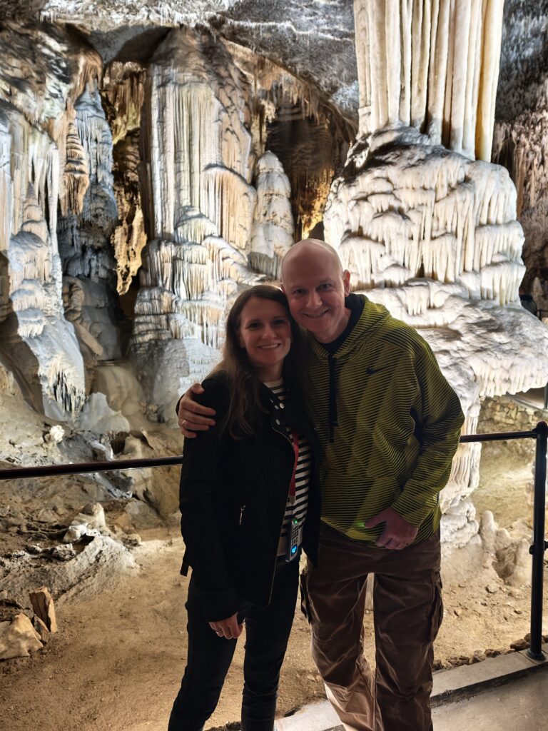 Turyści na tle białych stalagmitów w Jaskini Postojna