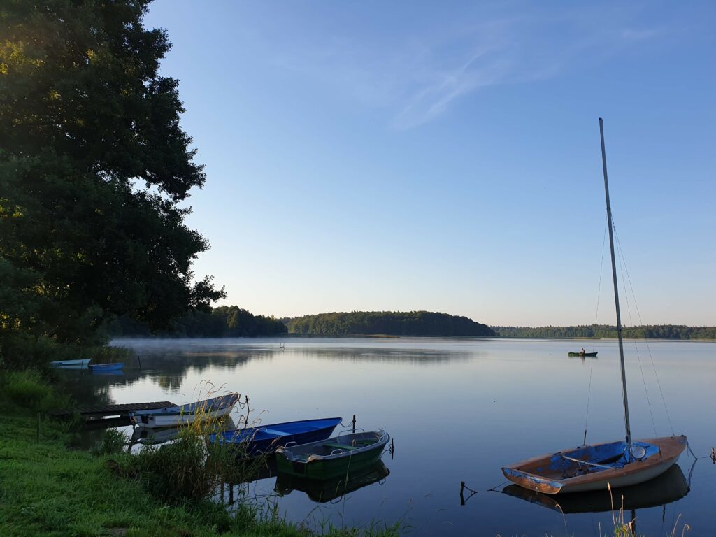 Poranna mgła nad jeziorem Gil i łodzie w Kotkowie, Warmia
