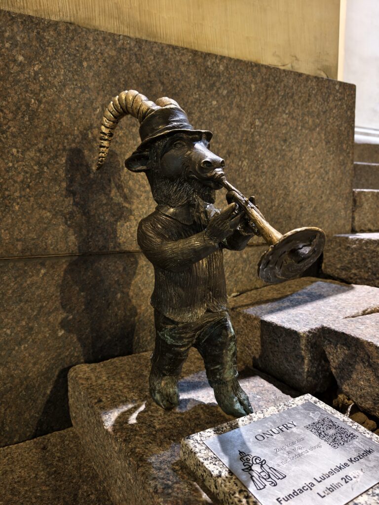 Brązowa rzeźba koziołka Onufry grającego na trąbce – jedna z figurek Koziołkowego Szlaku Legend w Lublinie