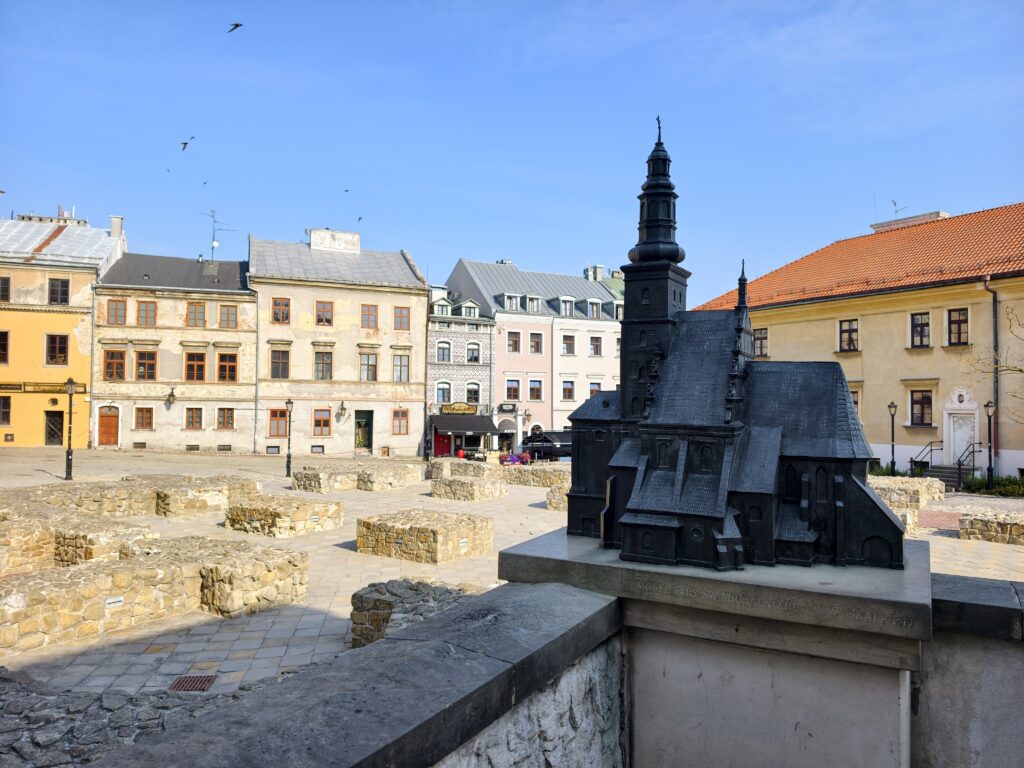 Czarny, metalowy model dawnego kościoła św. Michała stojący nad odsłoniętymi fundamentami na Placu Po Farze w Lublinie