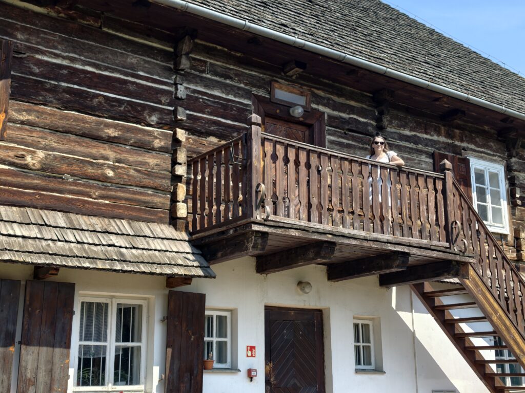 Zwiedzająca stojąca na drewnianym balkonie zabytkowego dworu w Muzeum Wsi Lubelskiej