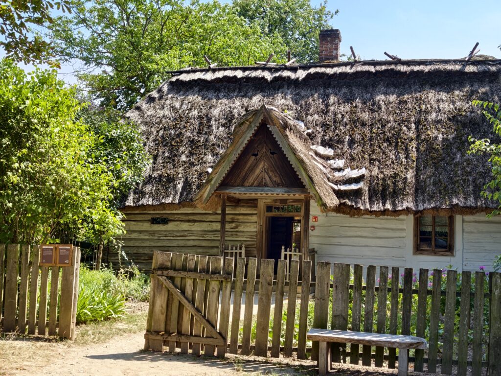 Chałupa kryta strzechą z ozdobnym drewnianym szczytem i motywem bocianów, Muzeum Wsi Lubelskiej