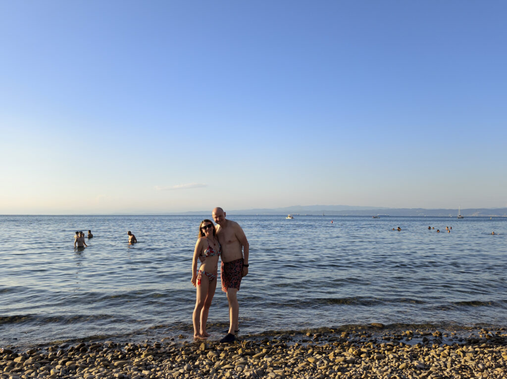 Para wypoczywająca na kamienistej plaży w Fiesie na tle błękitnych wód Adriatyku.