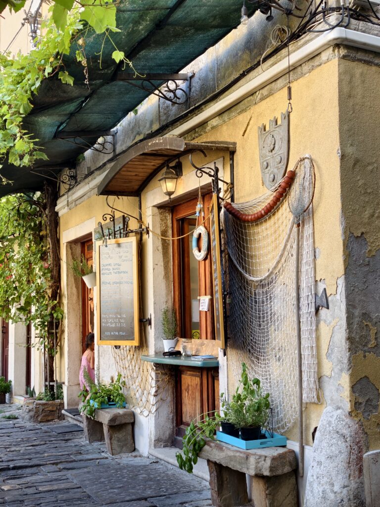 Wejście do kultowej restauracji Fritolin Pri Cantini w Piranie, ozdobione rybacką siecią i tablicą z menu.