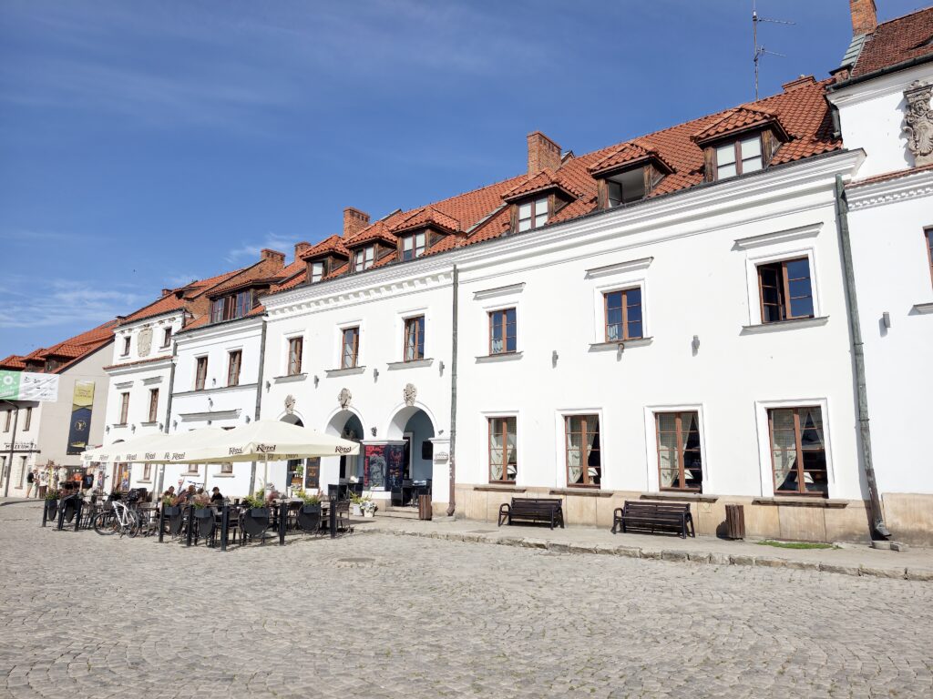 Rząd białych zabytkowych kamienic z czerwonymi dachami przy Rynku w Kazimierzu Dolnym