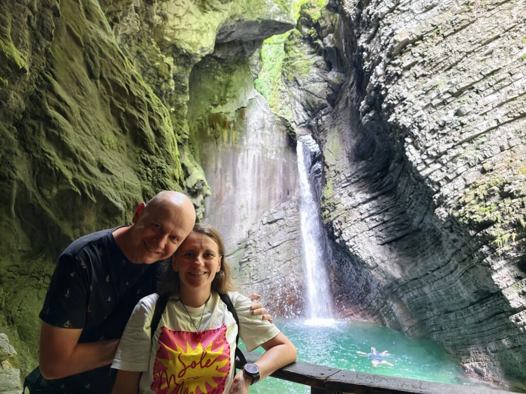 Para turystów pozująca do zdjęcia na tle wodospadu Kozjak w Słowenii