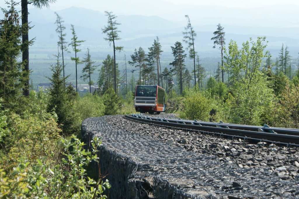 Wagonik kolejki terenowej jadący po torach ze Starego Smokowca na Hrebienok, w tle dolina i zabudowa miejscowości